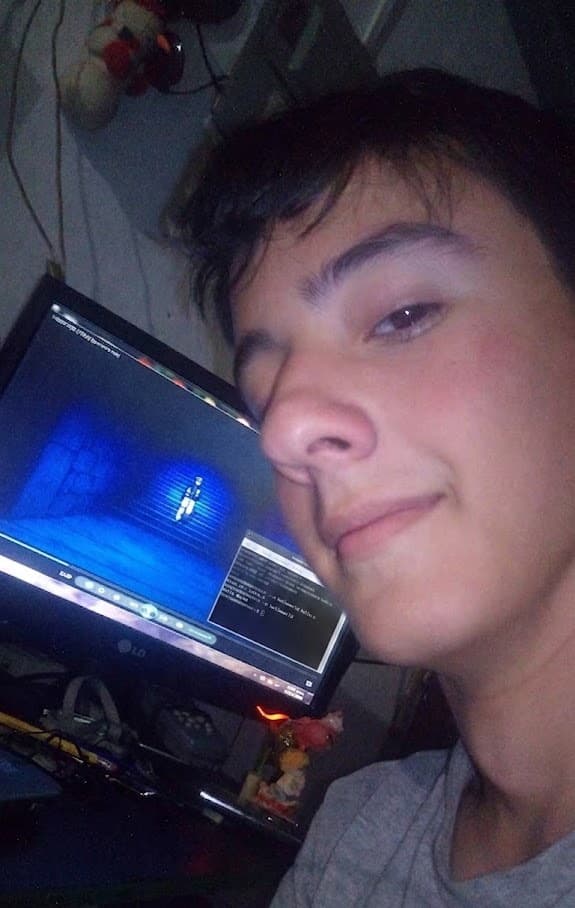 A close selfie at night, lit by the monitor beside me with a game paused on screen.