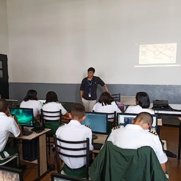 A classroom of uniformed students at computers, with me at the front beside a diagram projected on the wall.